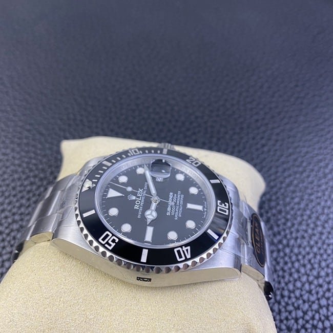 Clean factory top replica Rolex men's watch, black dial, steel strap, black Submariner, automatic movement, side view.